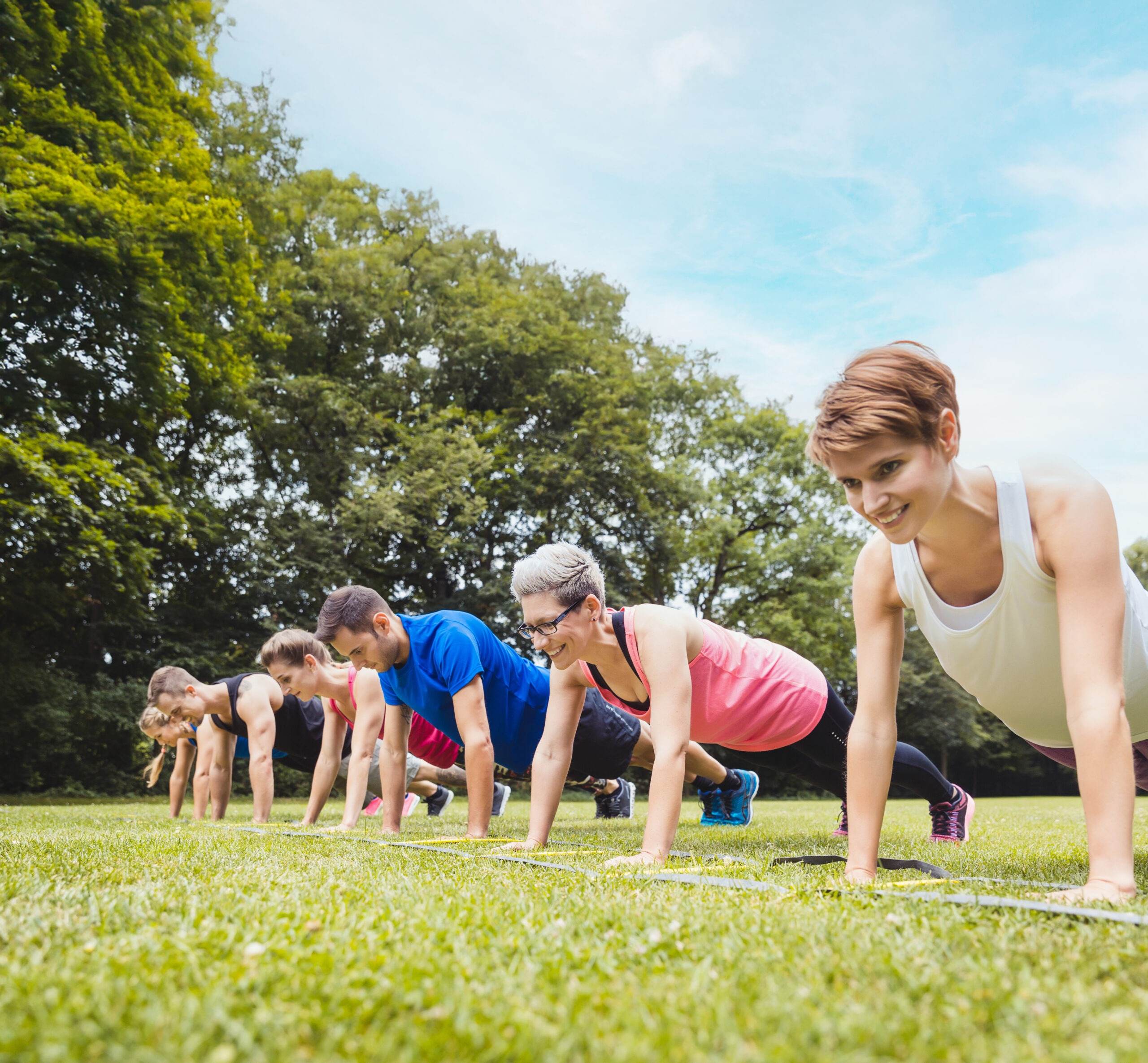 Fitness group practising push-ups in park